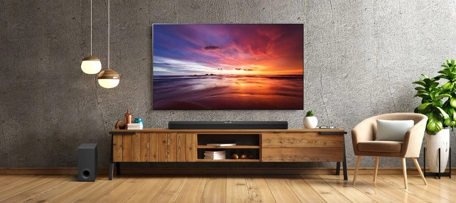 The LG S90TR Soundbar set up under a premium television and near a compatible subwoofer.