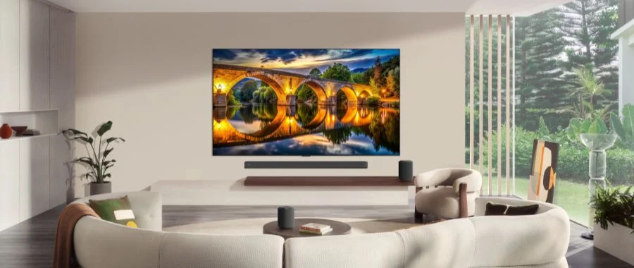 LG G6 TV and a soundbar mounted on a wall with a tan sectional in the foreground.