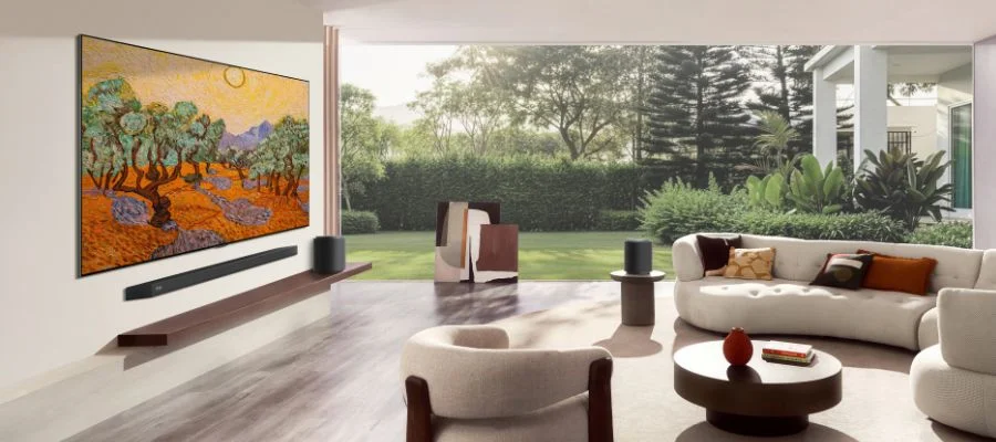 LG G6 TV mounted on a wall above a soundbar in a modern living room with floor-to-ceiling windows.