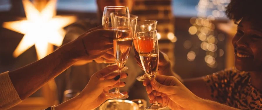 Four glasses clinking in celebration, with people out of focus