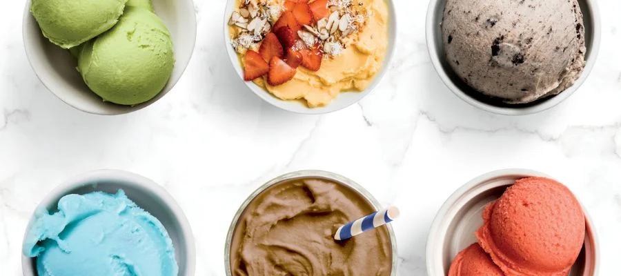 Six frozen treats in bowls; green ice cream, a smoothie bowl, a cookie mix-in, colorful sorbets and a chocolate shake.
