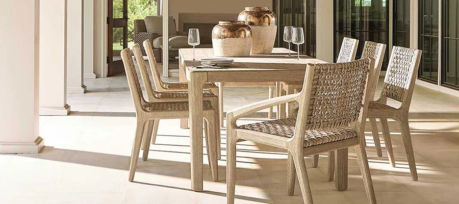 beige rattan dining chairs seated around a light wood dining table on patio