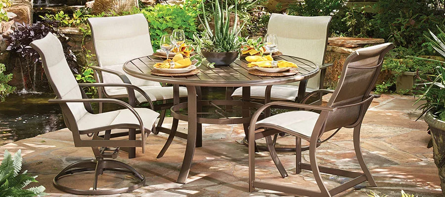 Four outdoor sling chairs around a round outdoor dining table.