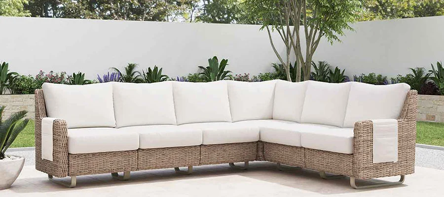 Beige outdoor sectional on patio with greenery in the background