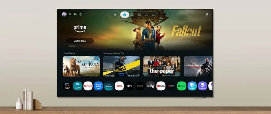 Samsung M70H TV with home screen displayed hanging on the wall above a TV stand.
