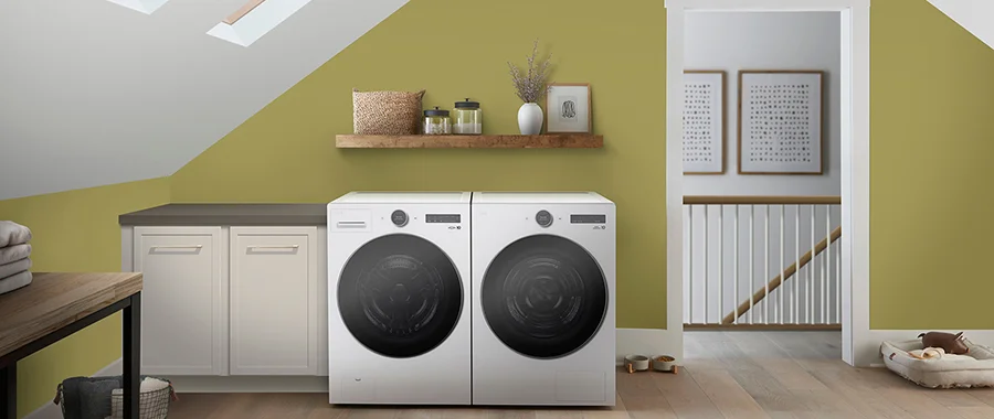 A white front loading washer and dryer sitting in a green room upstairs