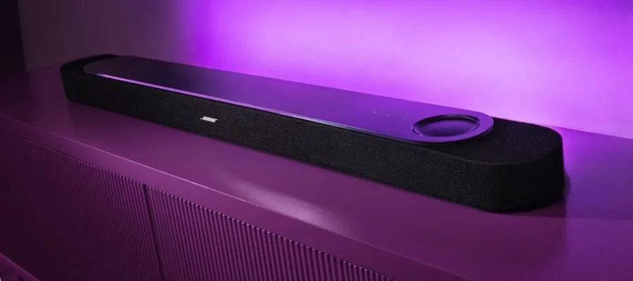 The black Bose Lifestyle Ultra soundbar resting on a console table beneath a TV in a living room.
