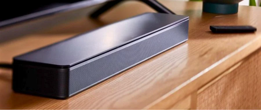 The Bose TV Speaker installed under a TV and resting on a wooden TV stand.