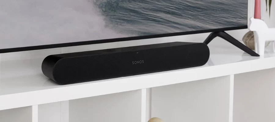 The Sonos Ray sitting on a white TV stand, under a flat screen TV.