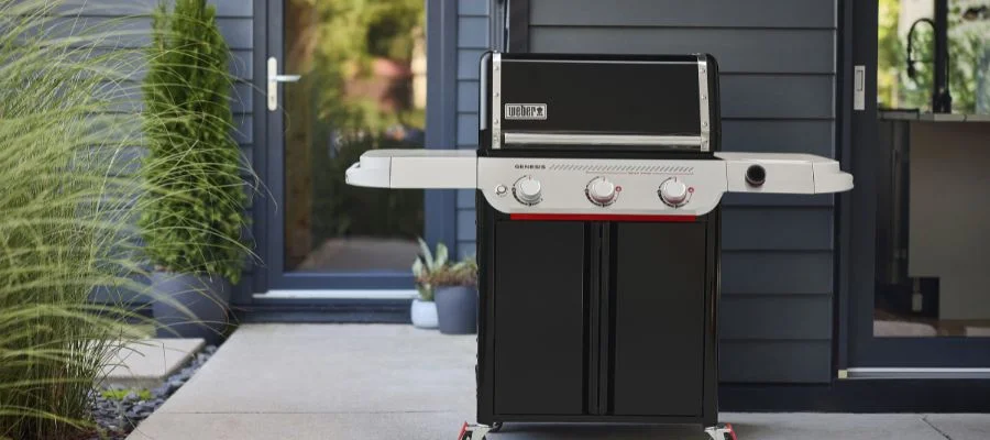 A three-burner Weber Genesis grill at rest on the patio in enameled black