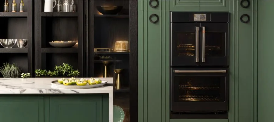 A matte black Cafe wall oven in a kitchen with green cabinets and whtie marble counters.