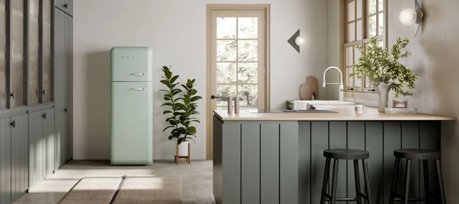 A mint green Smeg retro refrigerator in a kitchen with sage green cabinets.