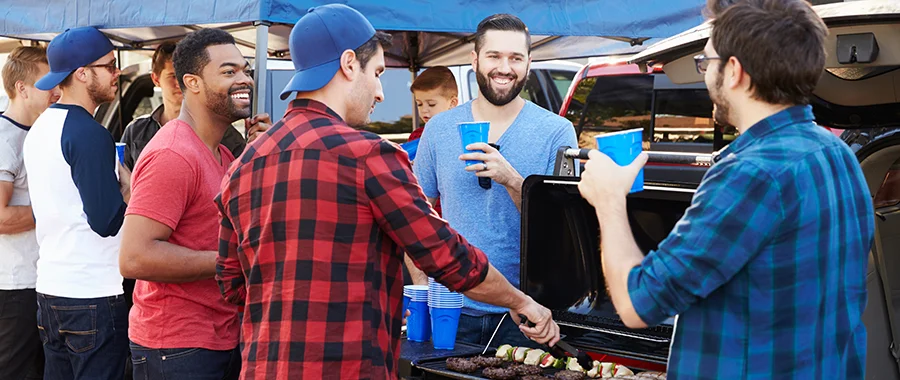 A group of men grilling food at a football tailgate party