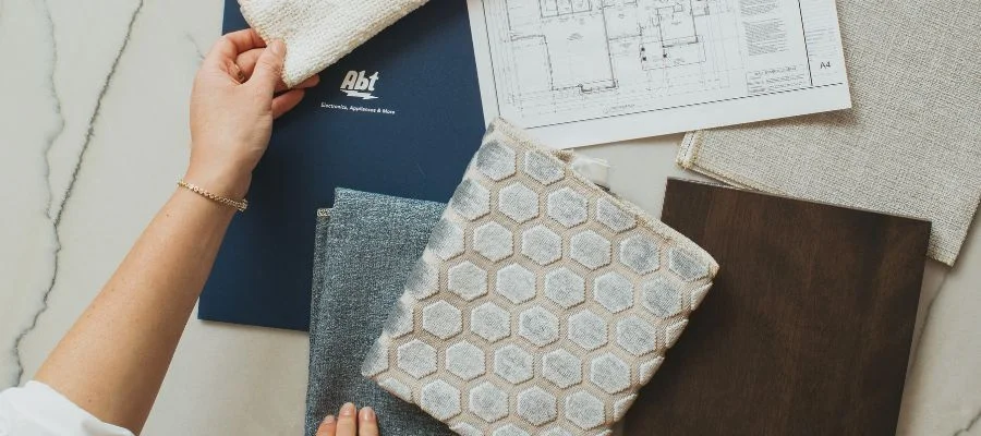 Plans for a home beside different fabrics and an Abt folder.