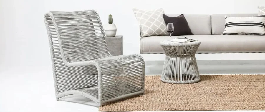 Patio with gray rope chair and matching side table with a gray outdoor loveseat in the background.