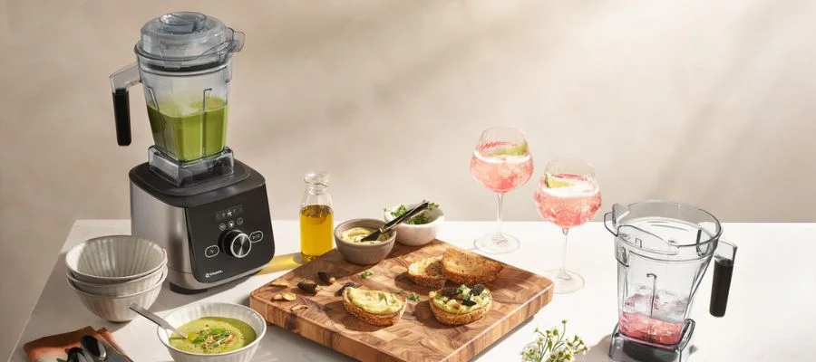 The Vitamix Ascent X4 series with a blended green soup beside a mother's day lunch complete with crostini, cocktaiils and another Vitamix blender container