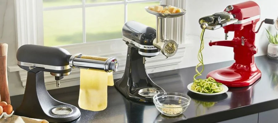 Three KitchenAid stand mixers showing off the pasta roller, grinder and spiralizer attachments.