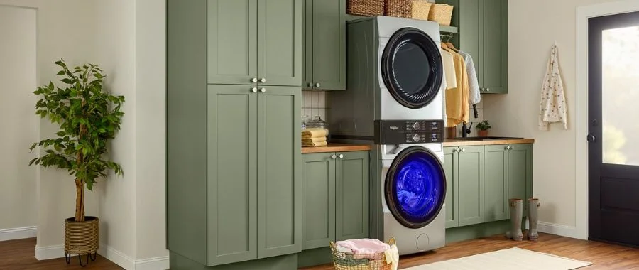 Stainless steel Whirlpool laundry tower in a laundry room with green cabinets.