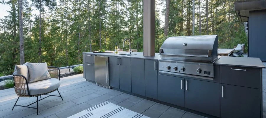 An outdoor kitchen complete with DCS grill, a compact outdoor refrigerator, faucet and sink.