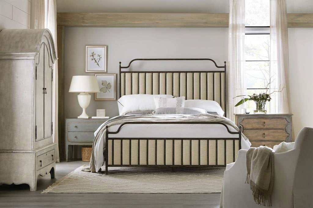 A white armoire in a bedroom with a bed and other furniture, from a distance