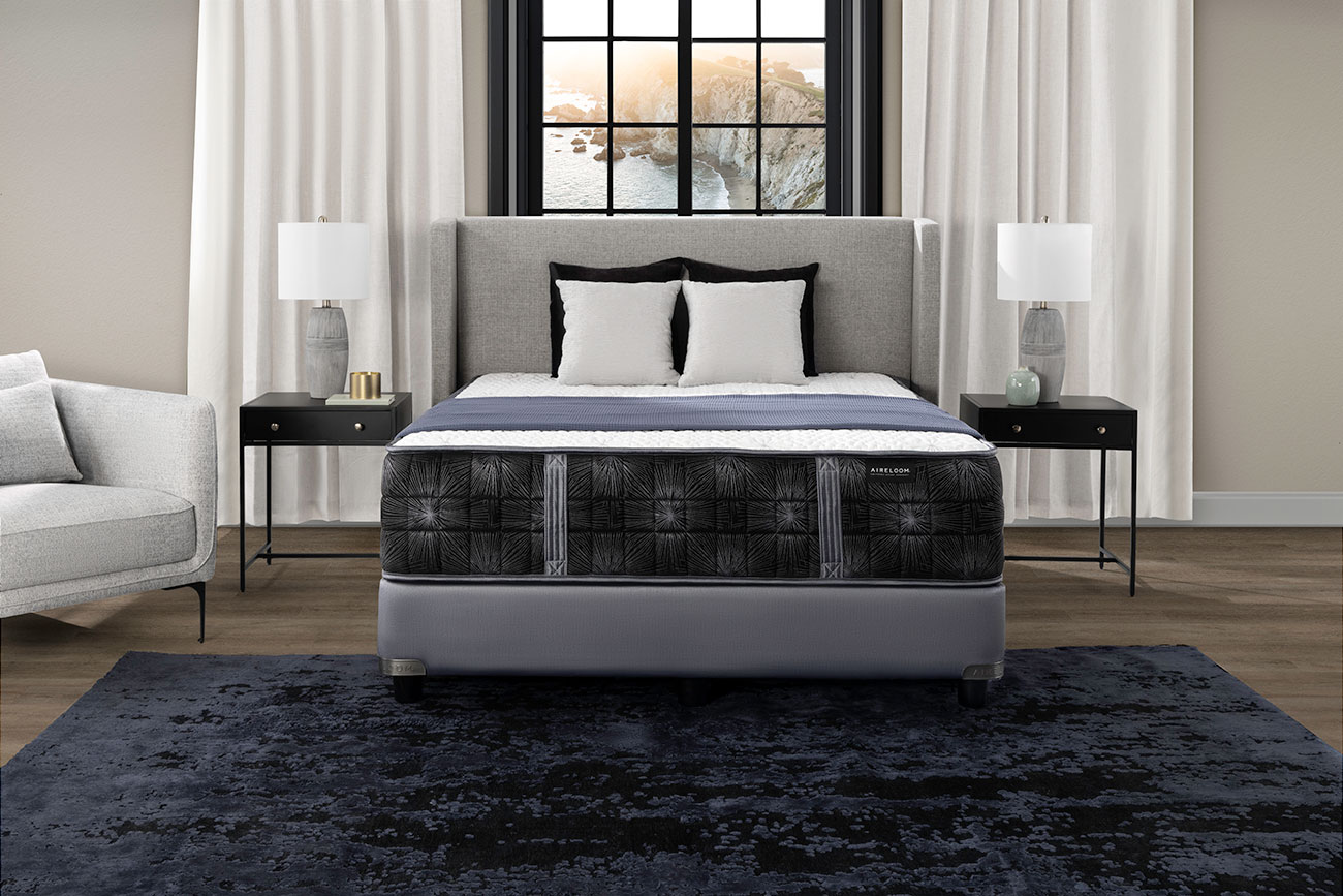 Close-up of mattress side detailing showing black patterned fabric and a small brand tag; gray edge piping visible.