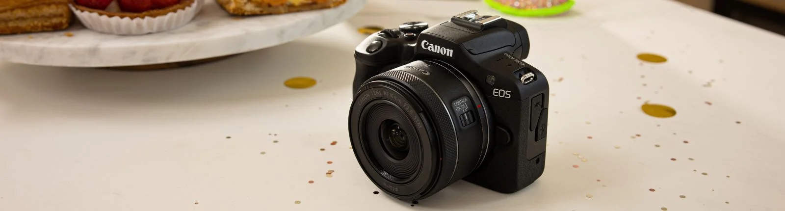 Black Canon EOS mirrorless camera on table with confetti.