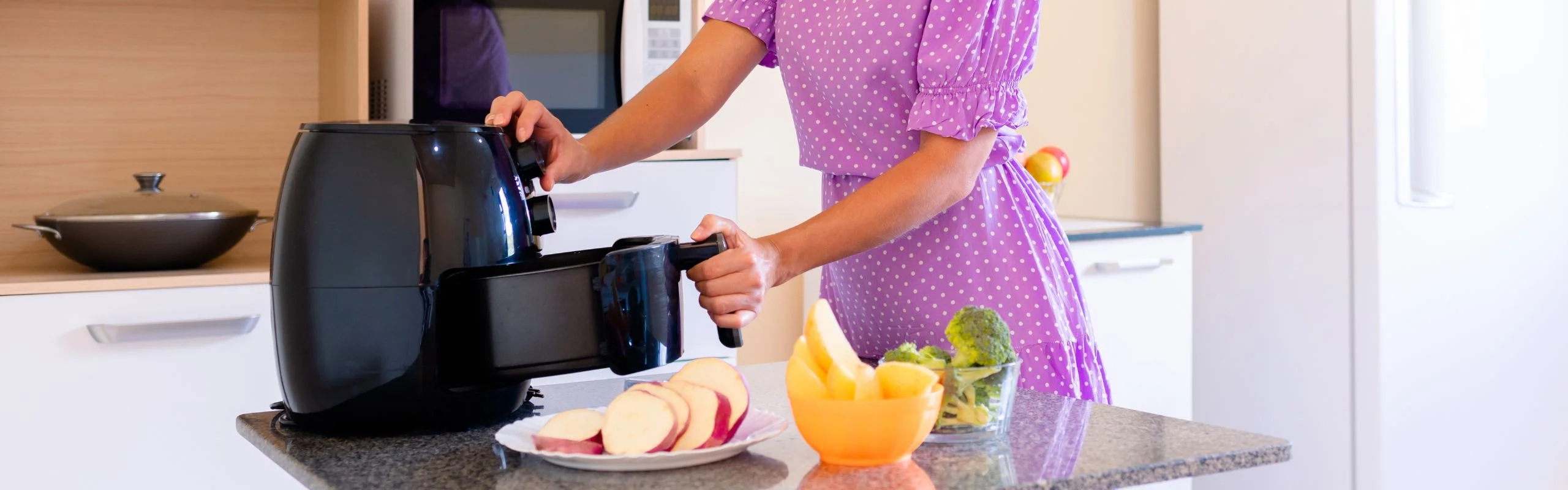 A woman using an air fryer to dehydrate various fruits.