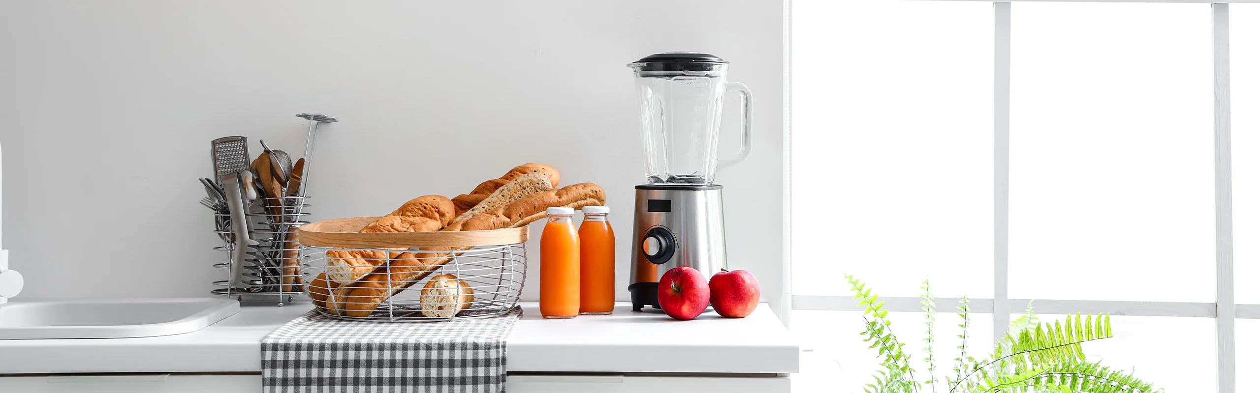 Blender sitting on kitchen counter next to fruit and bread.