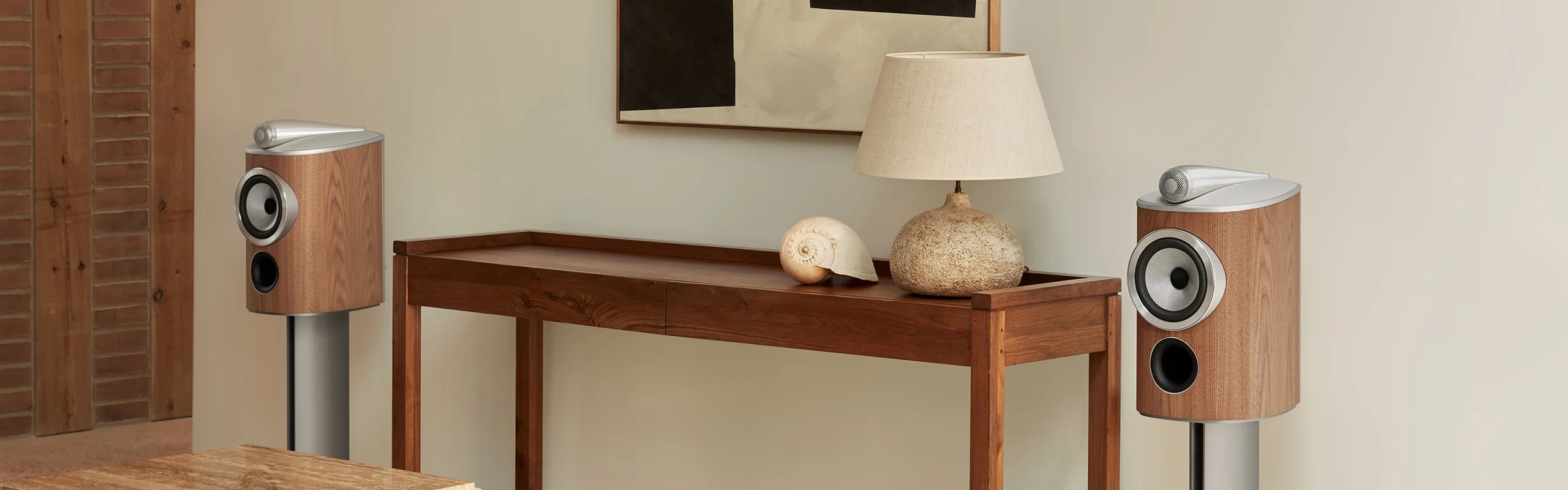 Two bookshelf speakers with a wood finish mounted on stands in a living room