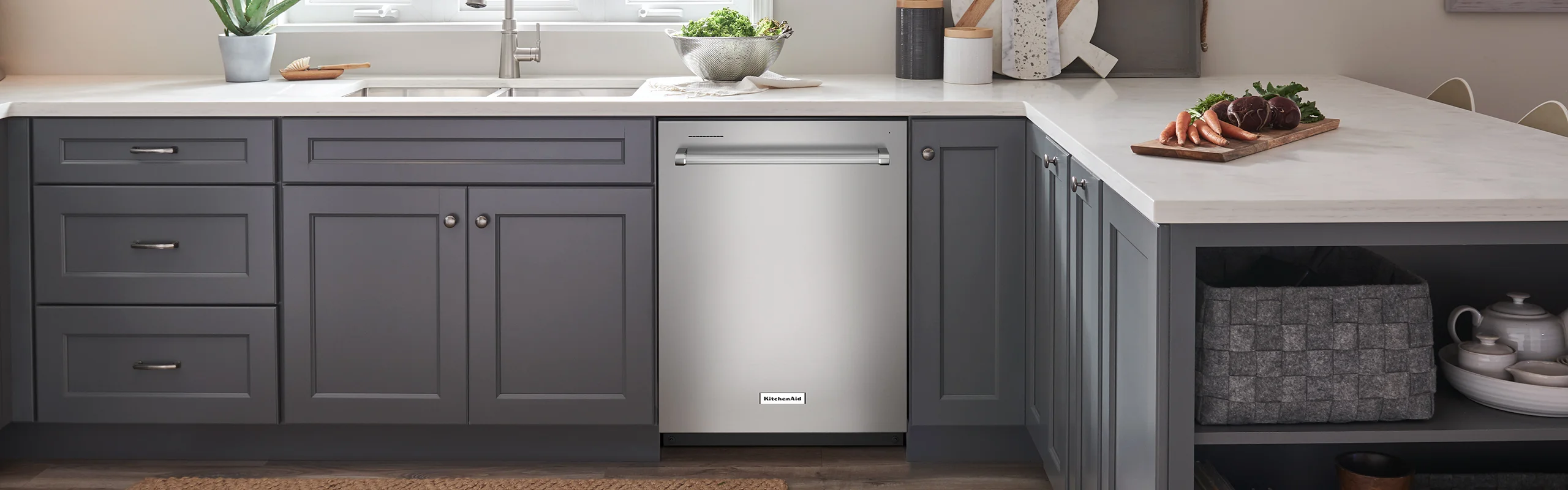 A silver stainless steel dishwasher built into gray kitchen cabinets