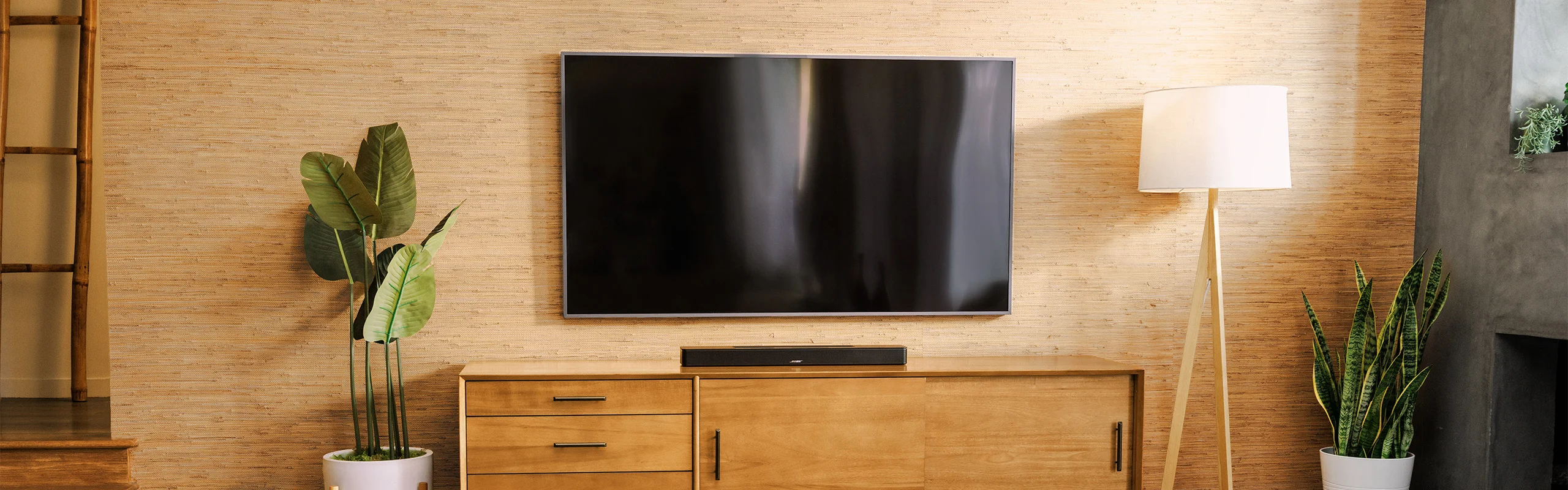 A living room wall with a mounted TV and a black soundbar sitting beneath it on a TV stand