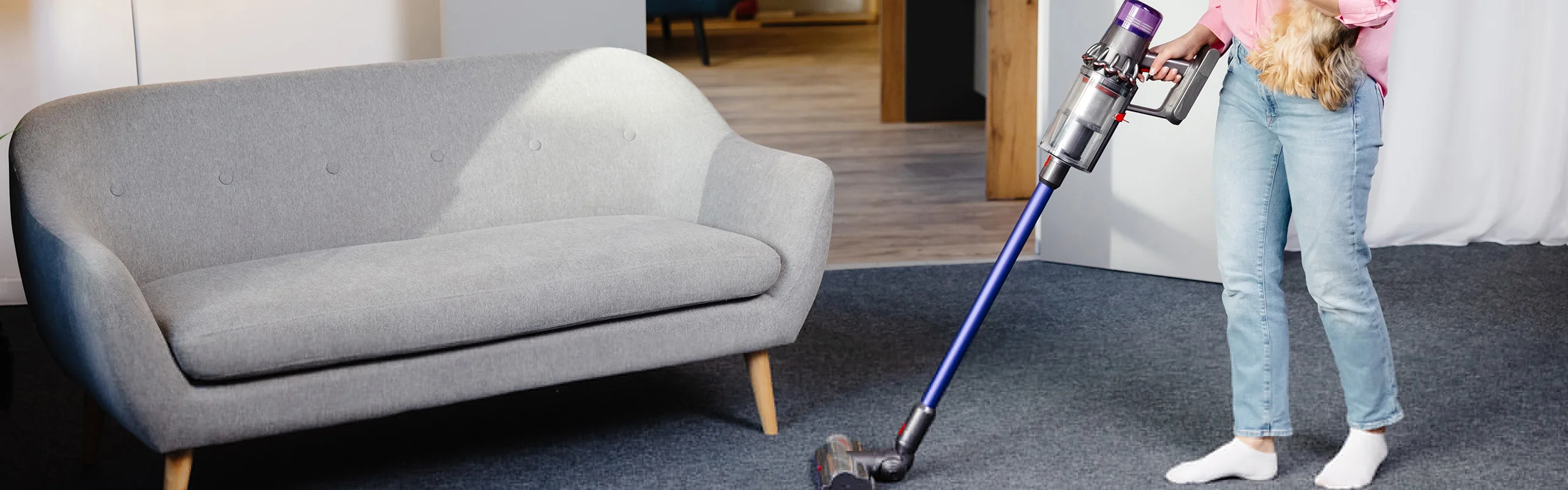 woman vacuuming carpet while holding Yorkie dog