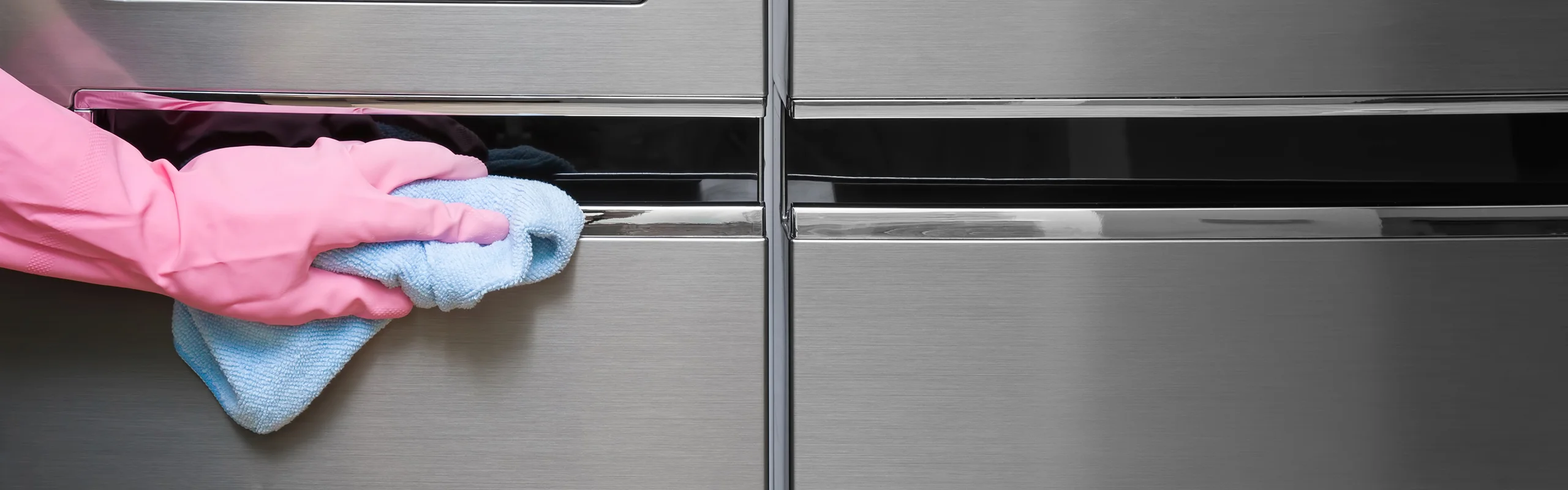 Pink gloved hand with towel cleaning appliances
