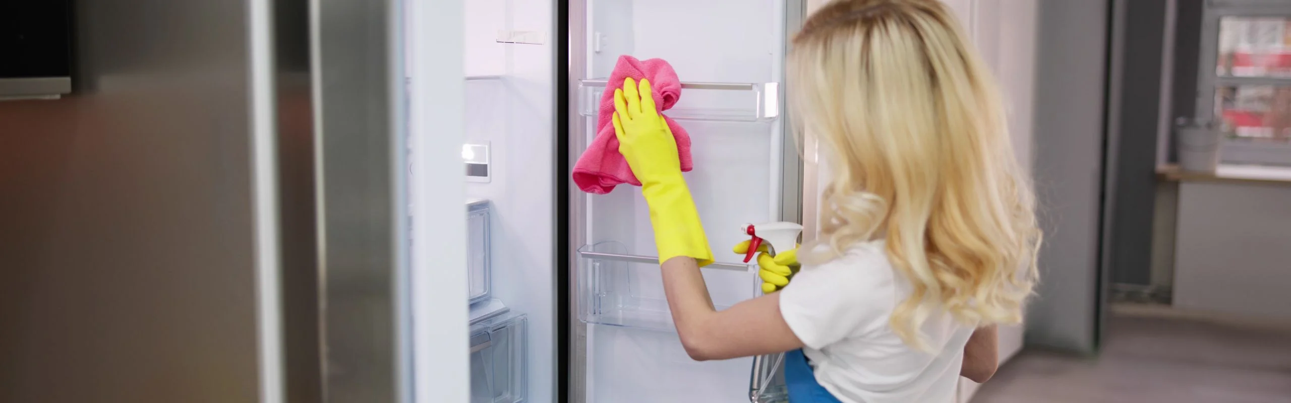 A woman cleaning the interior of her refrigerator.