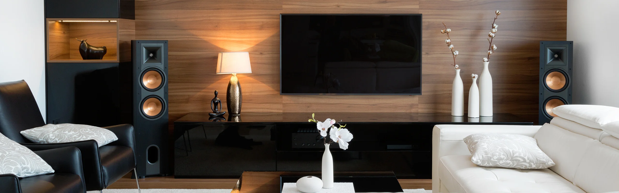 Living room with mounted wall TV with decor and large speakers on each side