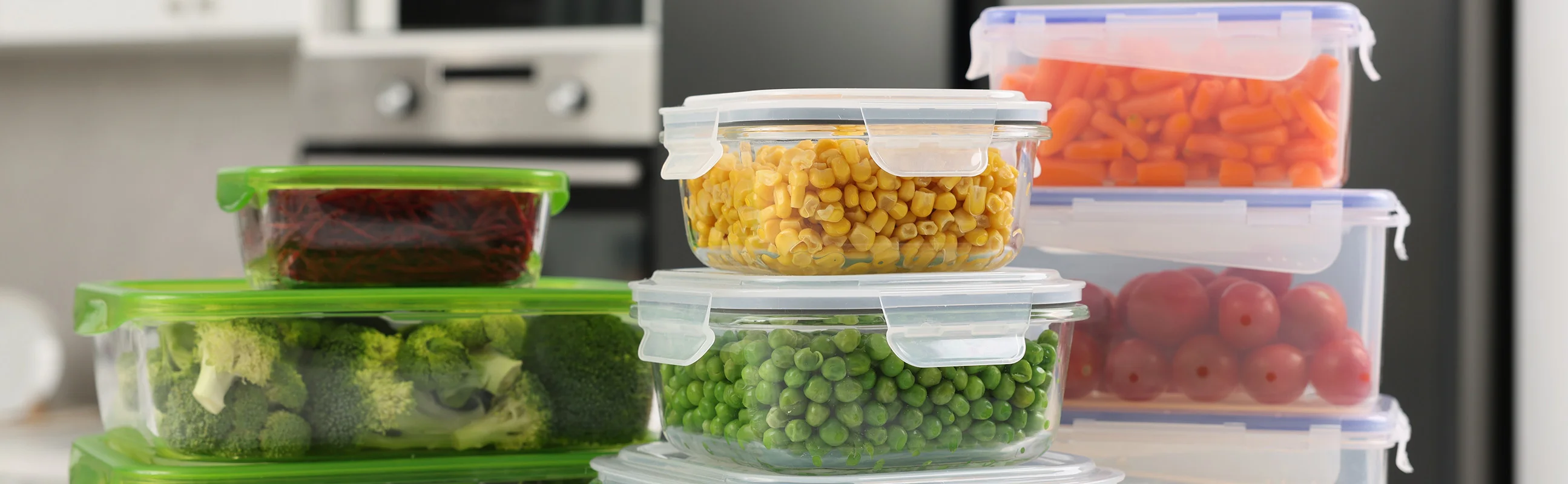 Various colorful vegetables inside clear glass storage containers that are stacked on top of one another