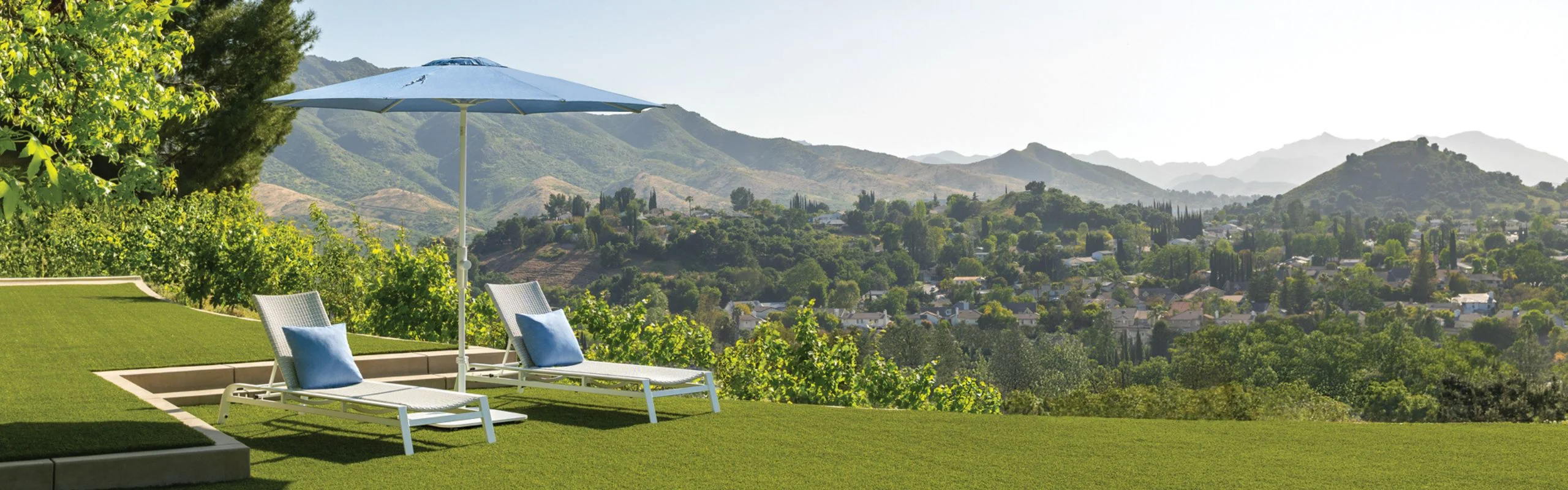 An umbrella shading two lounge chairs overlooking mountains in the background