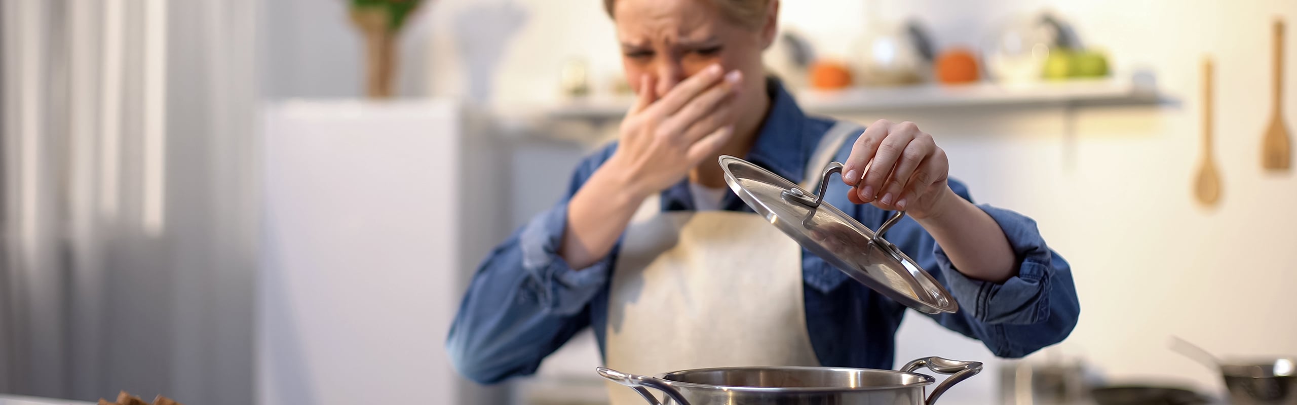 Woman covering face lifting pot lid