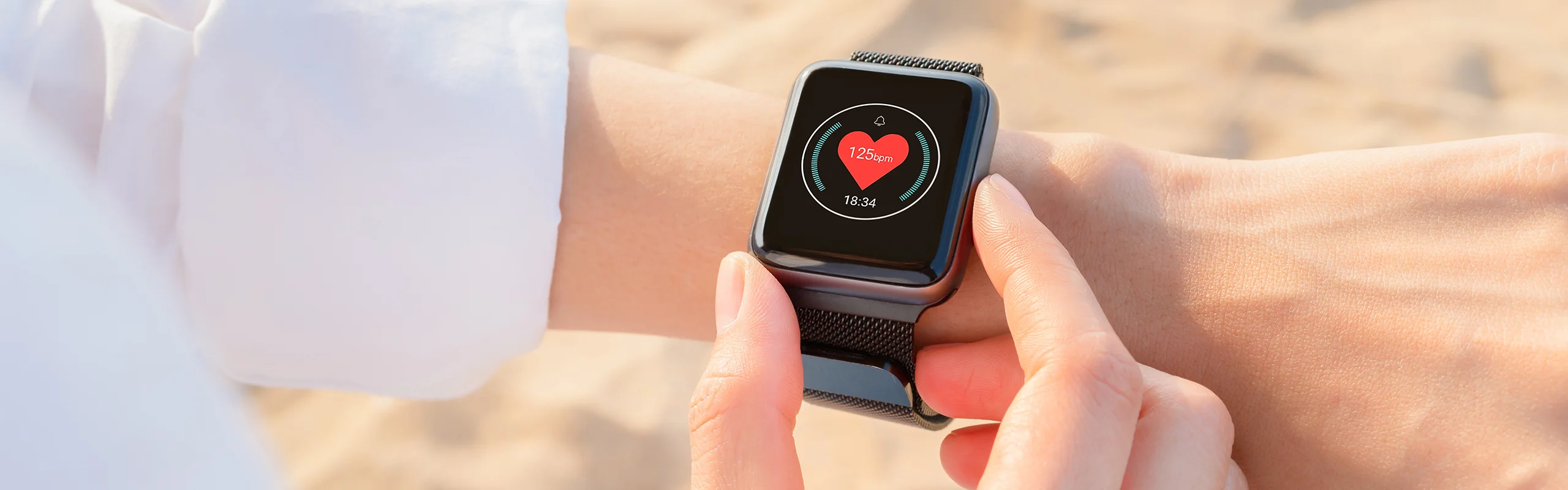 A wrist wearing a smartwatch that displays the user's BPM or heart rate on the screen