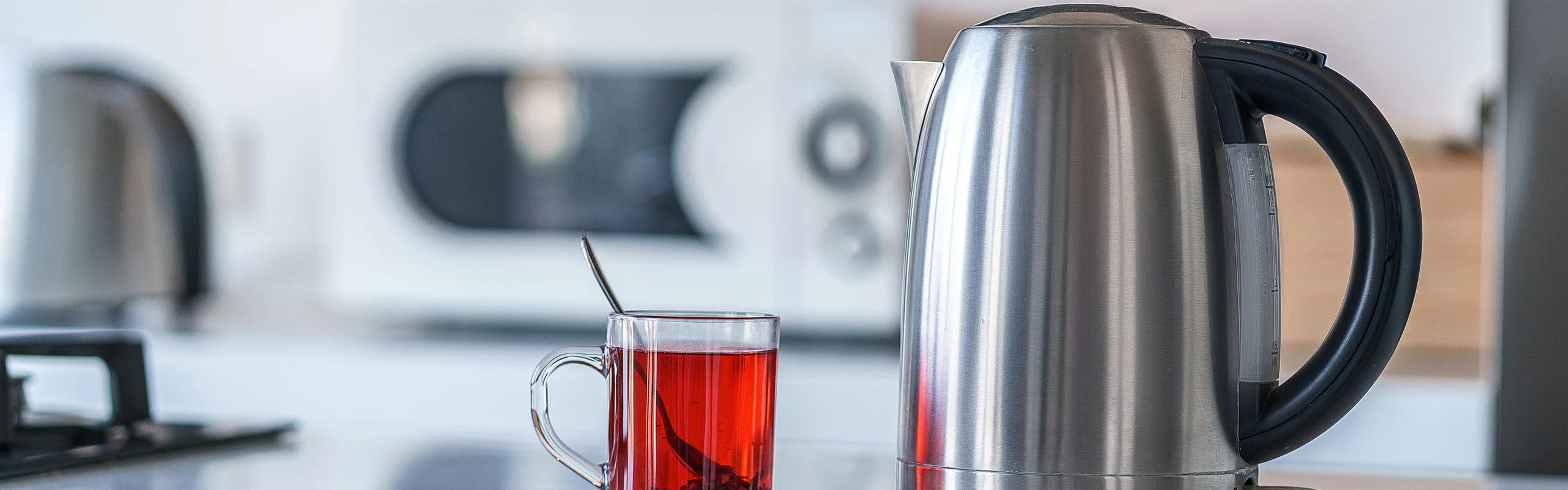 Silver water kettle next to cup with red liquid