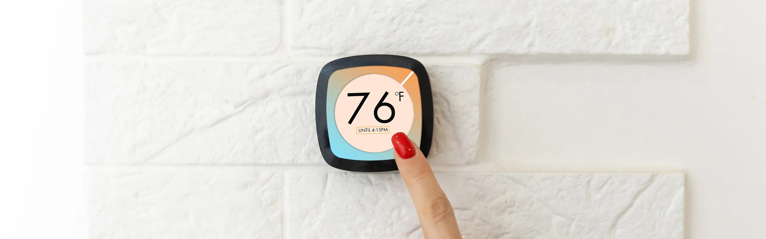 A finger tapping a smart thermostat with a screen display reading 76&deg;F until 4:15PM