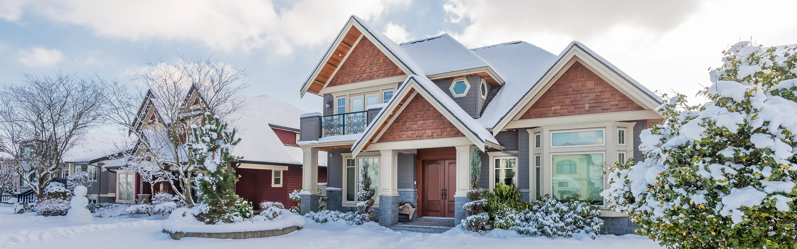 A picture of the outside of a home in winter with snow all around.