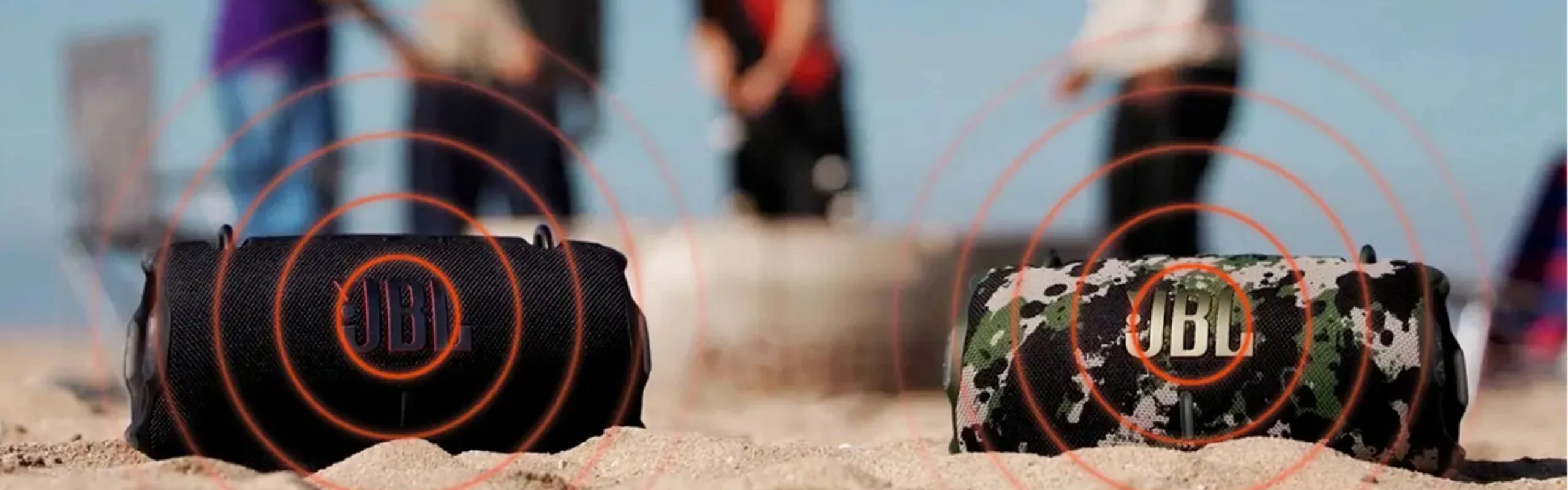 Two JBL speakers in the sand with graphic depicting sound waves emitting from each speaker.