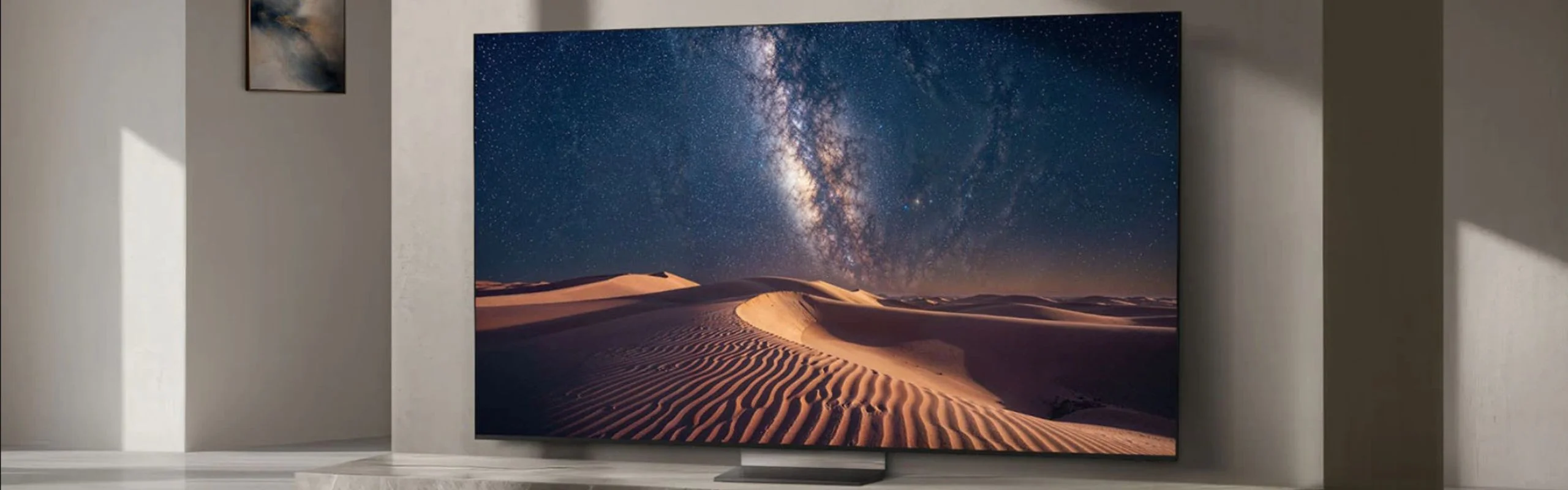 A Samsung R95H TV on a marble TV stand with a picture of a desert on screen.